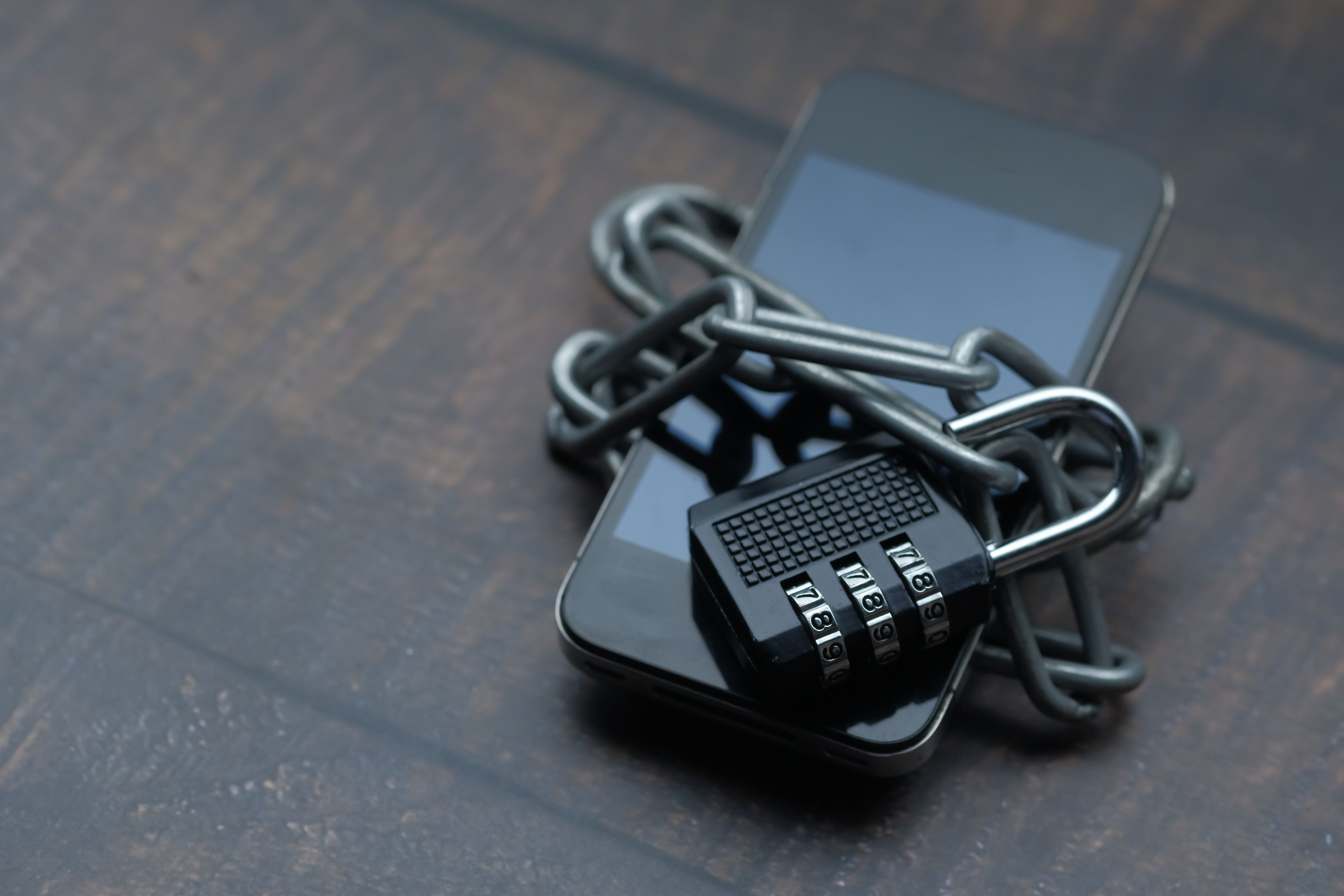 A smartphone secured with a chain and padlock, representing personal device privacy and digital boundaries.